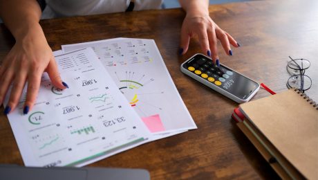 Cat costa sa ai o firmă , femeie tanara facnd calcule pe telefon cu un caiet cu cifre in fata